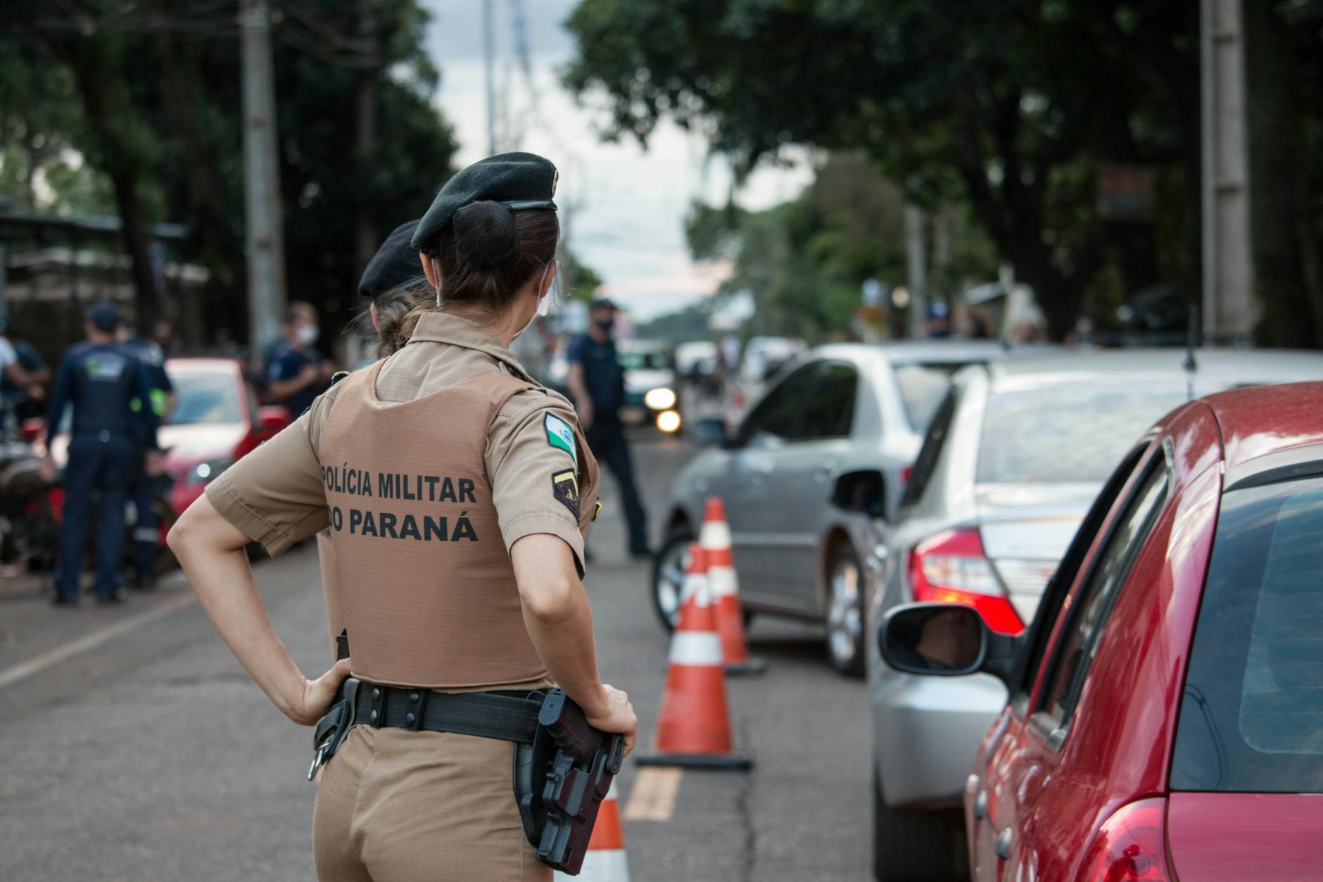 Back view of a police officer in uniform controlling traffic on a busy road.