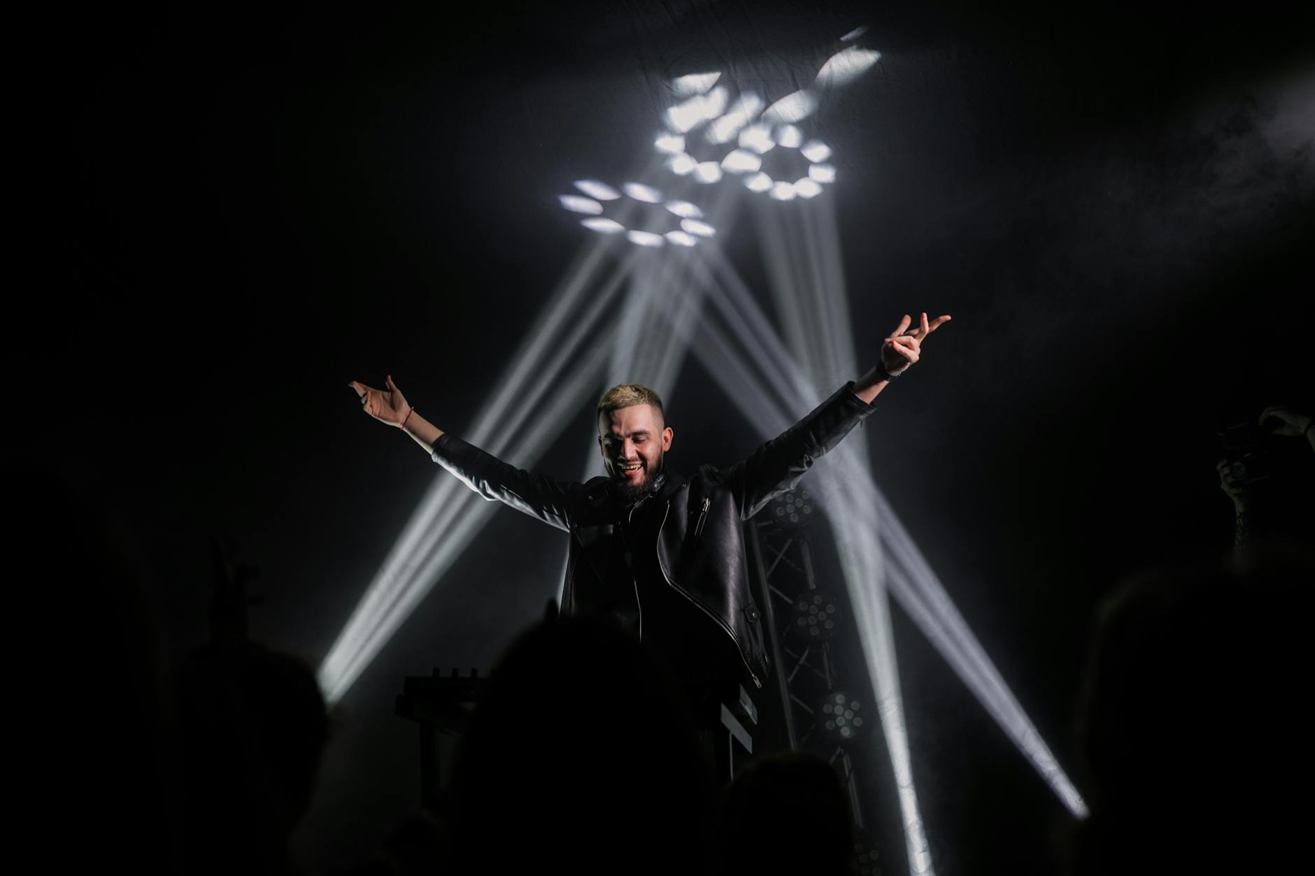 Energetic performer on stage illuminated by dramatic spotlights during a live show.
